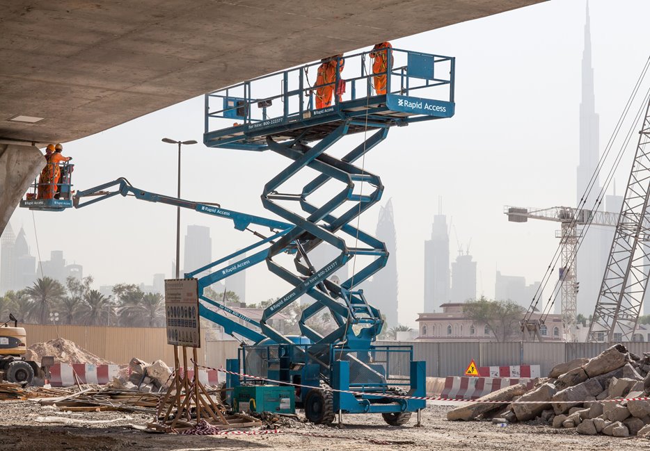 Manlift Genie AWP boom and scissor working on Dubai Water Canal UAE, Burj Khalifa in background